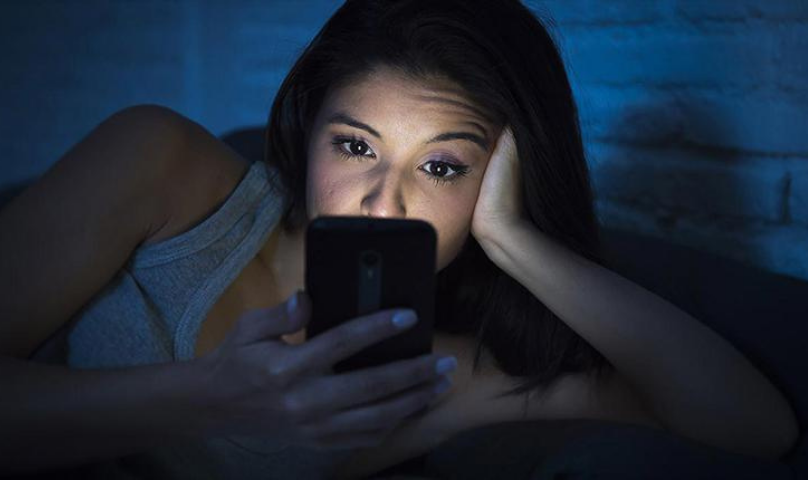 women in be next to partner but on phone in the dark