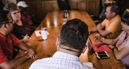 group of people of various ethnicities talking around a table in discussion