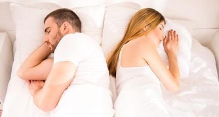couple in bed with backs turned to each other