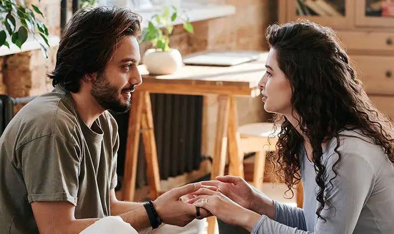 couple holding hands across a table and talking