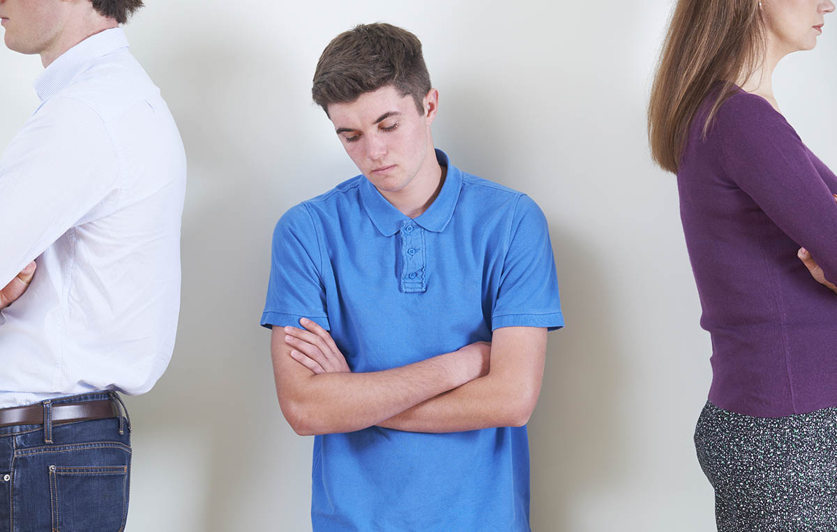 sad teen boy with parents facing away angrily