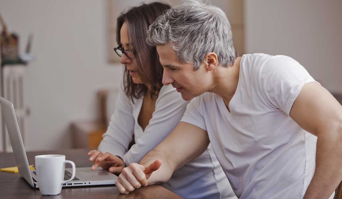 couple in kitchen looking at laptop screen