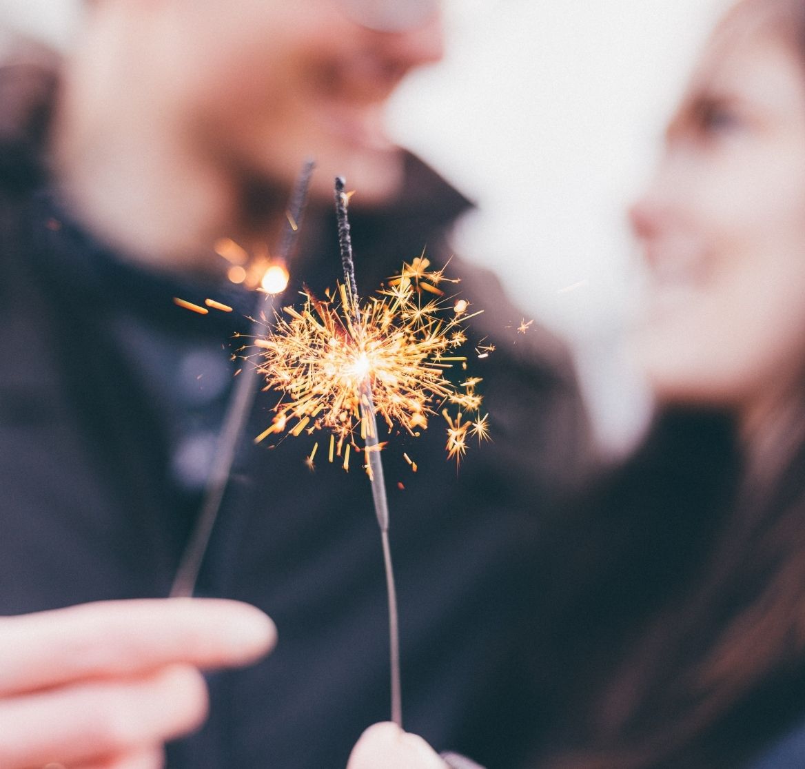 couple smiling at each other holding sparklers
