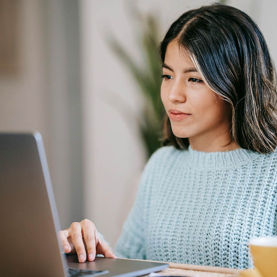 woman in grey jumper on laptop