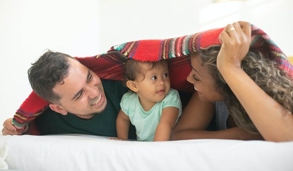 parents with small child with learning disability playing under a sheet