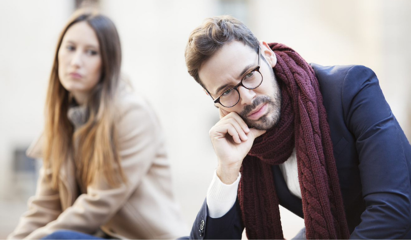 sad woman looking over at angry male partner who is looking away from her